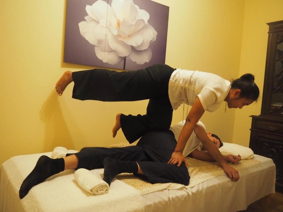 A therapist using assisted stretching technique during a traditional Thai massage, a hallmark of the practice