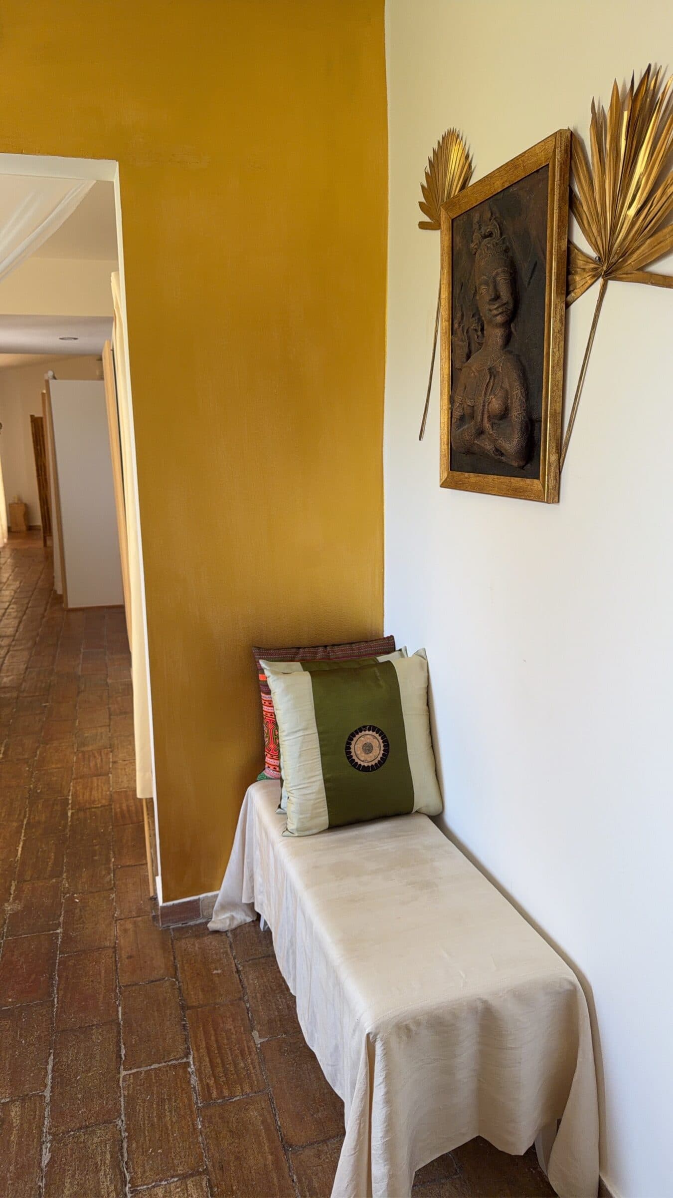 A gold-walled corner with a framed Buddha relief and gilded palm fronds