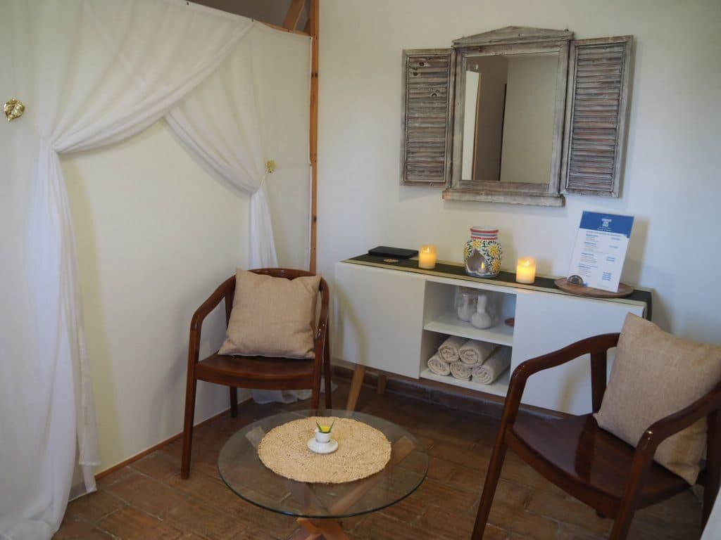 A waiting nook with a shuttered mirror and cushioned chairs
