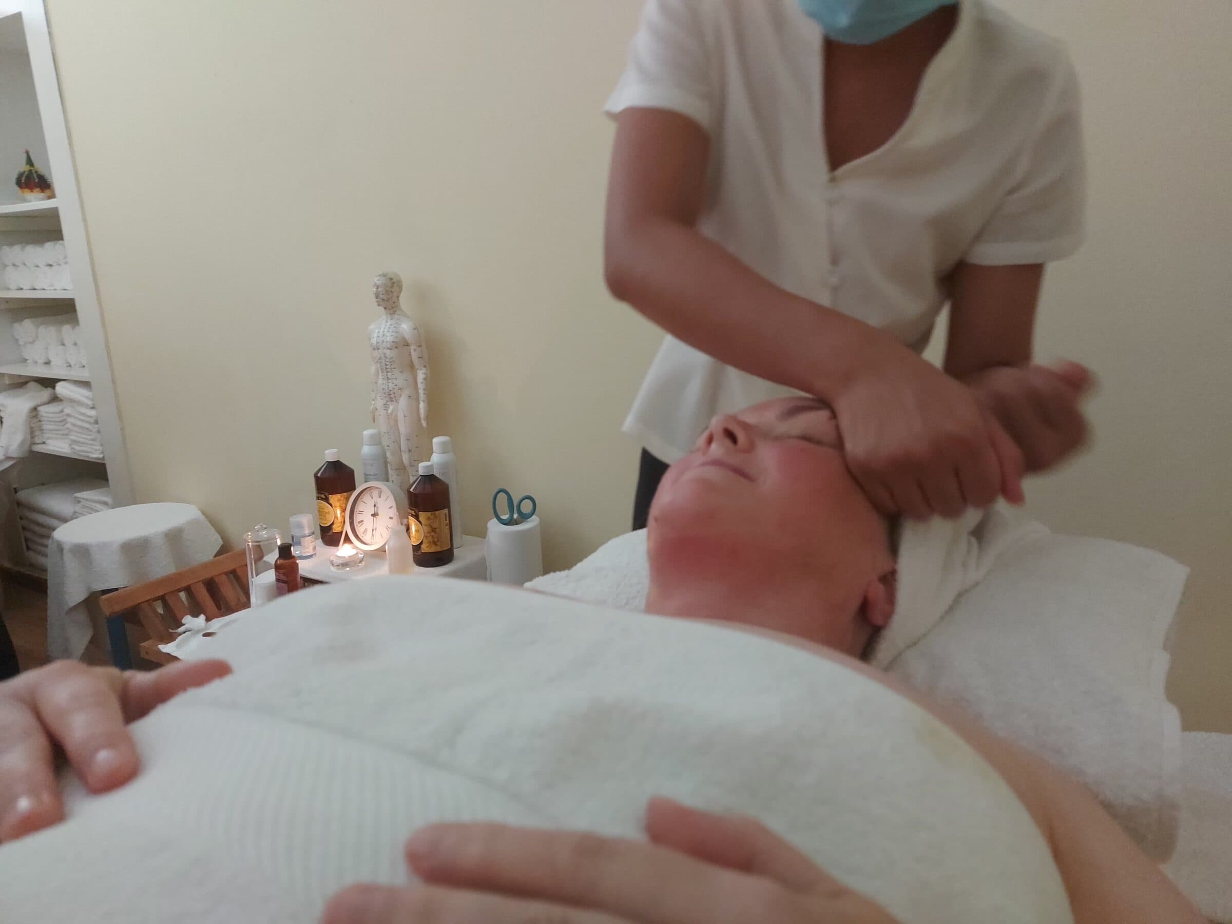 A therapist giving a head massage, close and warmly lit