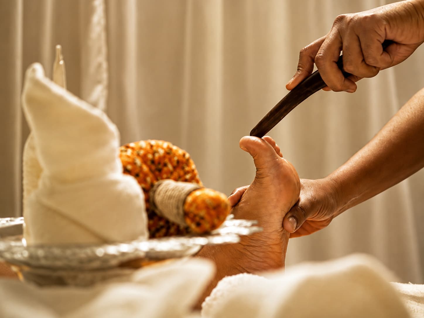 Traditional Thai foot reflexology using a wooden massage tool, worked systematically across the whole foot